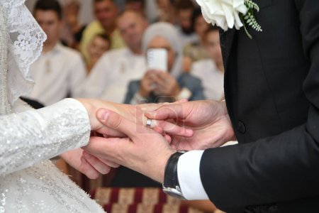 Téléchargez les photos : Un gros plan du marié mettant une sonnerie sur le doigt de la mariée pendant la cérémonie - en image libre de droit