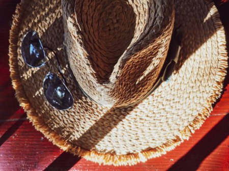 Foto de Una vista superior de gafas de sol sobre un sombrero de paja de verano - Imagen libre de derechos