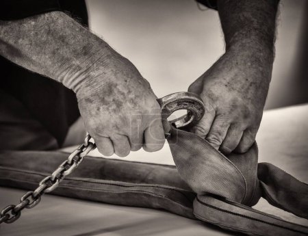 Photo for A sepia of hands of a man connecting the hook to an industrial sling - Royalty Free Image