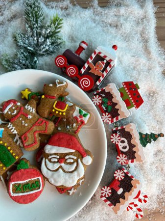 Téléchargez les photos : Une vue de dessus des biscuits de Noël doux avec le Père Noël et un train mis sur la table avec de la neige artificielle - en image libre de droit