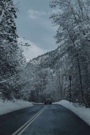Téléchargez les photos : Un camion roulant sur une route dans une belle scène d'hiver avec des collines boisées à l'horizon à Provo - en image libre de droit