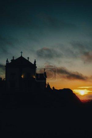 Foto de Una hermosa vista vertical de la silueta de la capilla Senhor Da Pedra durante la puesta de sol en Miramar - Imagen libre de derechos