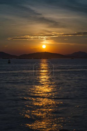 Téléchargez les photos : Un plan vertical du coucher de soleil doré qui brille au-dessus de la mer calme et de la montagne de l'Ananas - en image libre de droit