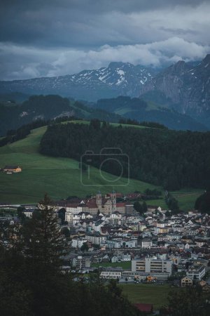 Photo for A vertical shot of a cityscape in green valley with mountains and cloudy sky - Royalty Free Image