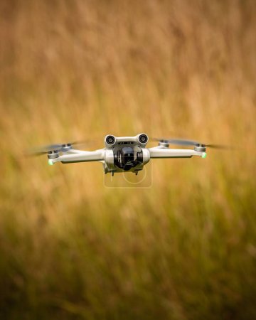 Photo for A selective vertical shot of a quadcopter flying over a blurry field - Royalty Free Image