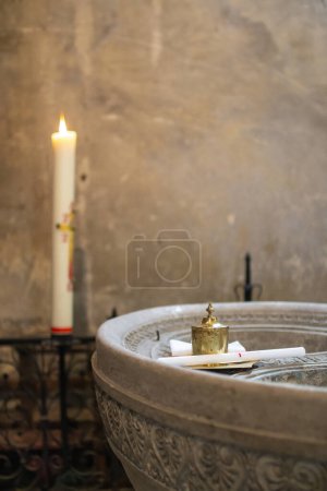 Téléchargez les photos : Un plan vertical de bougies et un petit étang d'eau pour le baptême chrétien à l'intérieur d'une église - en image libre de droit