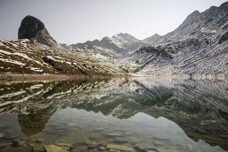 Téléchargez les photos : Un beau lac reflétant le ciel nuageux avec des montagnes enneigées en arrière-plan - en image libre de droit