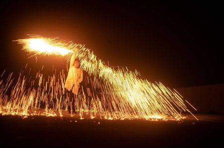 Téléchargez les photos : Un étudiant qui tourne des étincelles lors d'un spectacle d'incendie la nuit - en image libre de droit