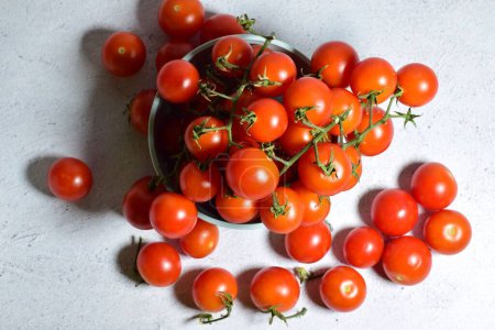 Foto de Una vista superior de tomates cherry jugosos regordetes en un tazón en la superficie de piedra - Imagen libre de derechos
