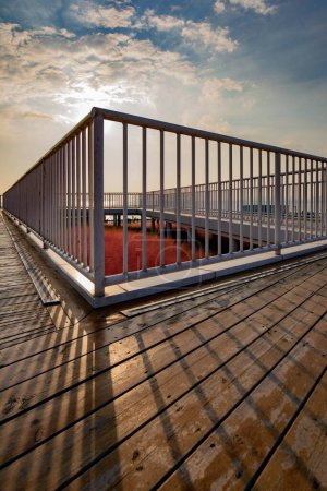 Téléchargez les photos : Plan vertical d'un sol en bois avec clôture métallique blanche au coucher du soleil. - en image libre de droit