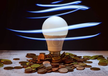 Foto de Una bombilla con concepto de monedas de consumo de electricidad - Imagen libre de derechos