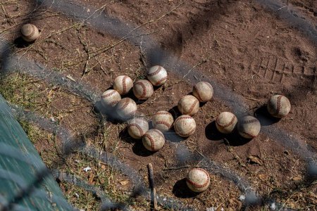 Foto de Muchas bolas de béisbol en el suelo de tierra a través de la cerca de rejilla de metal - Imagen libre de derechos