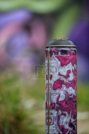 Foto de Un primer plano de una lata de metal con una pared de graffiti en el fondo - Imagen libre de derechos