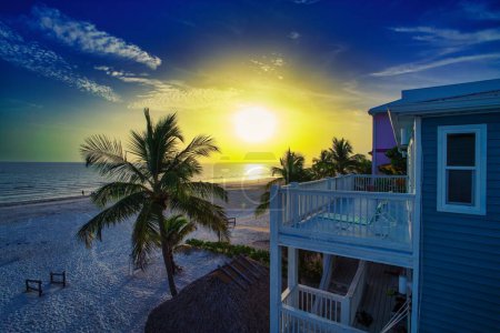 Foto de Una casa y palmeras en la playa contra la puesta de sol escénica en Florida, EE.UU. - Imagen libre de derechos