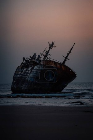 Photo for A vertical shot of a historic dirty old ship after a shipwreck on a seashore - Royalty Free Image