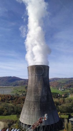 Téléchargez les photos : Une centrale nucléaire avec des panaches de fumée qui en sortent contre un magnifique paysage naturel - en image libre de droit
