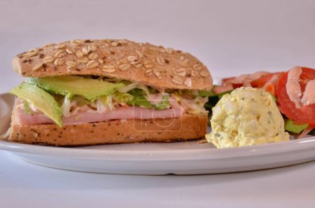 Photo for A close-up shot of a sandwich with ham and avocado served with a side salad and scrambled eggs - Royalty Free Image