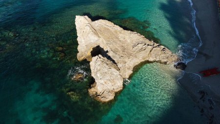 Un disparo aéreo de dron de un mar azul con una enorme formación rocosa en Monterosso al Mare, La Spezia, Italia