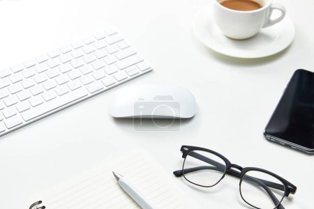 Téléchargez les photos : Une vue de dessus d'une table de bureau blanche avec un ordinateur portable, des lunettes et une tasse de café - en image libre de droit
