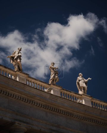 Téléchargez les photos : Les statues des saints et des martyrs sur la place Saint-Pierre sous le ciel nuageux bleu de la Cité du Vatican - en image libre de droit