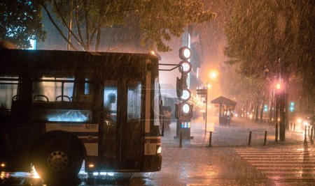 Photo for A bus driving on the street in a rainstorm night - Royalty Free Image