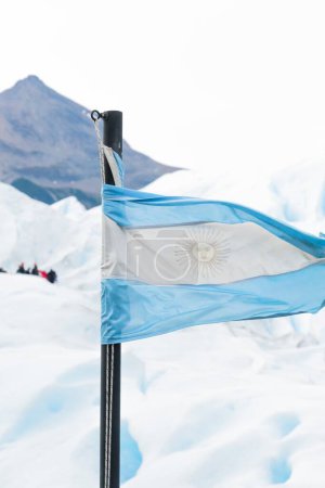 Foto de Un plano vertical de la bandera argentina con fondo de nieve - Imagen libre de derechos