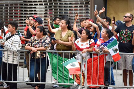 Téléchargez les photos : Un groupe de personnes avec un drapeau regardant une performance pendant le défilé de la fête de l'indépendance du Mexique - en image libre de droit