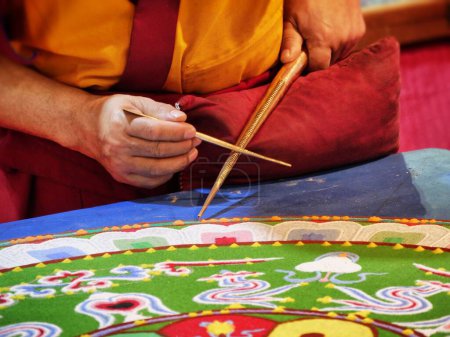 Téléchargez les photos : Un gros plan d'un moine bouddhiste créer mandala avec des sables multicolores - en image libre de droit