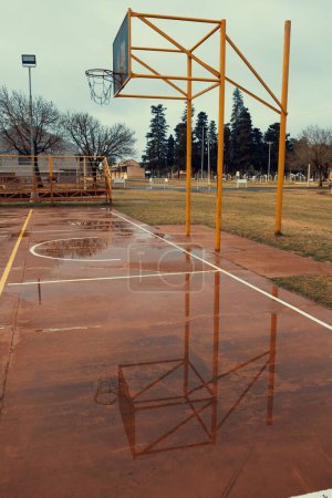 Photo for A vertical shot of a basketball court with puddles after rain - Royalty Free Image