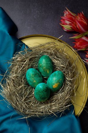 Téléchargez les photos : Une vue rapprochée des œufs de couleur verte sur une assiette décorée comme un nid pour la célébration de Pâques - en image libre de droit