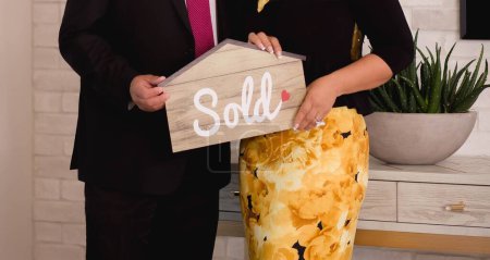 Photo for A couple holding a house-shaped paper with the word sold printed on it - Royalty Free Image