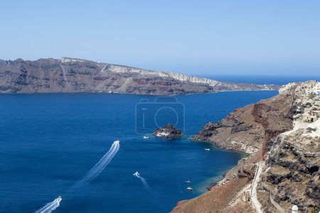 Téléchargez les photos : Vue aérienne des falaises au bord de l'eau du village d'Oia par une journée ensoleillée - en image libre de droit