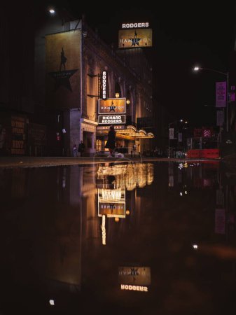 Téléchargez les photos : Plan vertical d'une flaque d'eau reflétant des bâtiments illuminés à New York - en image libre de droit