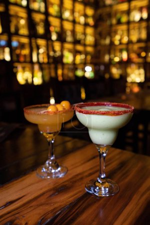 Foto de Un trago vertical de dos bebidas alcohólicas afrutadas sobre una mesa de madera en un club nocturno - Imagen libre de derechos