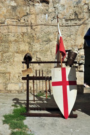 Foto de Un disparo vertical del engranaje templario medieval con una bandera, escudo y casco contra el castillo en Trogir - Imagen libre de derechos