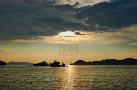 Téléchargez les photos : Une vue panoramique des silhouettes de yachts flottant sur la mer sous les forts rayons du soleil - en image libre de droit