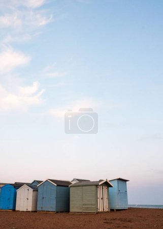 Téléchargez les photos : Quelques cabanes de plage à la lumière du jour sur la plage de Teignmouth sur fond de ciel nuageux - en image libre de droit