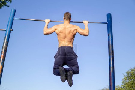 Photo for A muscular Caucasian man workout pull ups at outdoor - Royalty Free Image