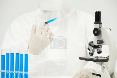 Photo for A doctor working with an optical microscope in a medical laboratory with test tubes on the table - Royalty Free Image