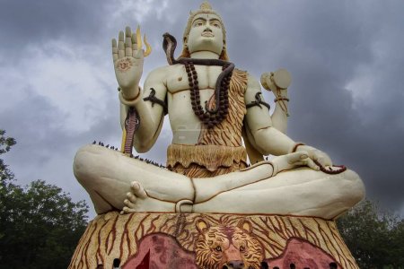 Foto de Un ángulo bajo de una estatua blanca del Señor Shiva bajo un cielo nublado en Nageshwar Rd, Dwarka, Gujarat, India - Imagen libre de derechos