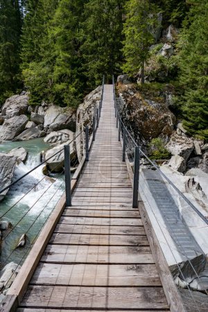 Téléchargez les photos : Plan vertical d'un pont en bois au-dessus d'une rivière dans la forêt. - en image libre de droit