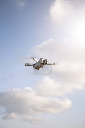 Photo for A vertical shot of a quadcopter flying in the sky in a sunny day - Royalty Free Image