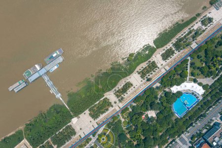 Téléchargez les photos : Une vue aérienne des bateaux au bord de la jetée sur la rivière et une végétation luxuriante sur le rivage - en image libre de droit