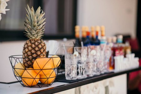 Téléchargez les photos : Une mise au point sélective d'un fruit à côté de verres et de bouteilles d'alcool sur fond flou - en image libre de droit