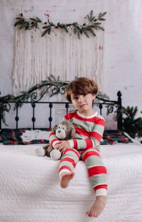 Téléchargez les photos : Un mignon bébé garçon caucasien assis sur le lit - en image libre de droit