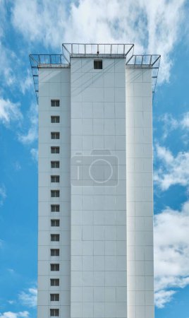 Foto de Un plano vertical de un edificio industrial blanco alto con ventanas en el fondo del cielo - Imagen libre de derechos
