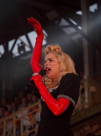 Foto de Una toma vertical de la hermosa Paloma Faith actuando en el hipódromo de Newmarket con sus guantes de látex rojo - Imagen libre de derechos