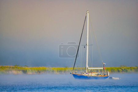Photo for A boat swimming in the Connecticut River during the foggy morning against the gray sky - Royalty Free Image