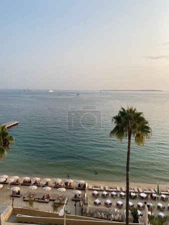 Foto de Una vista vertical de ángulo alto de una playa de arena con sombrillas, un café y palmeras frente al mar - Imagen libre de derechos