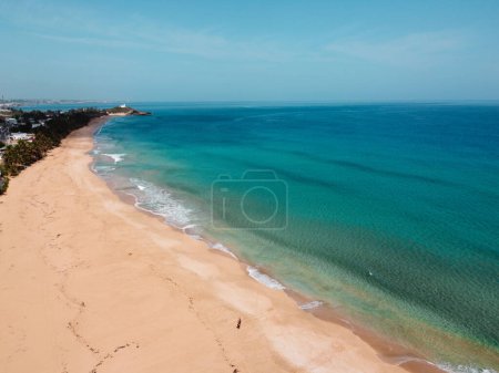 Téléchargez les photos : Vagues mousseuses calmes blanches s'écrasant sur une plage de sable par une journée ensoleillée - en image libre de droit